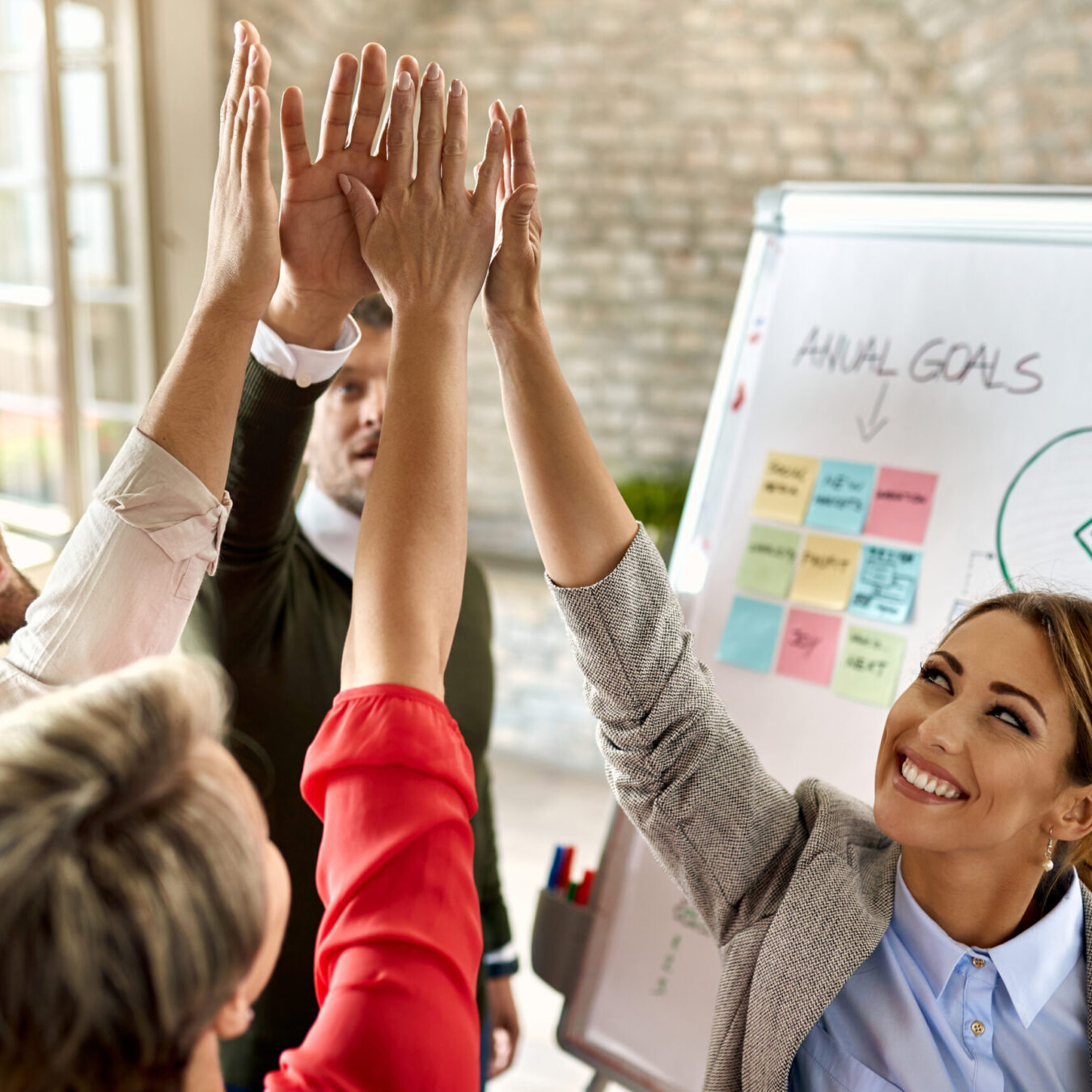 Happy business team with raised hands celebrating their success in the office.